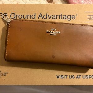 Coach long zip-around wallet made of brown or "saddle" colored leather.